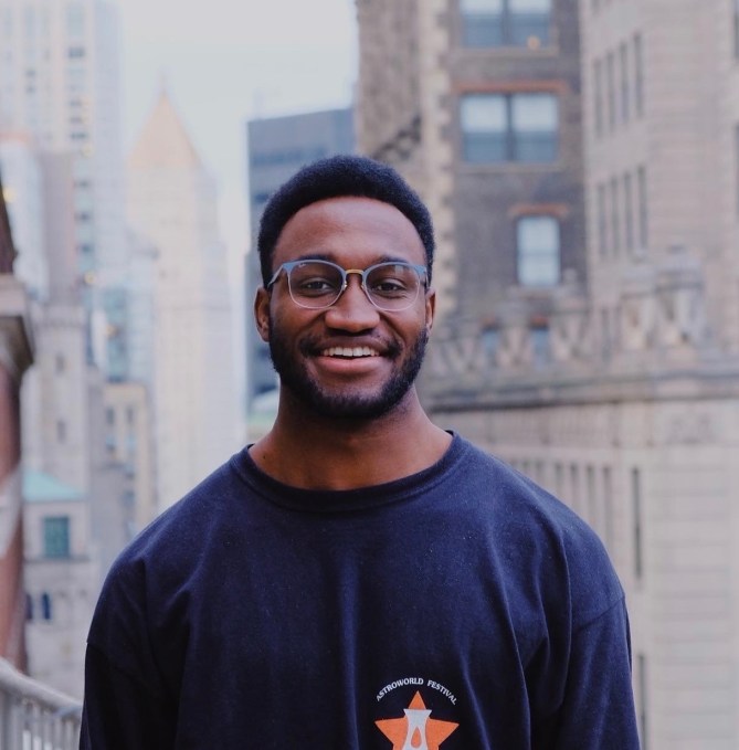 A black man with glasses smiles to the camera