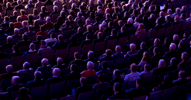 audience seated in a theater, facing stage