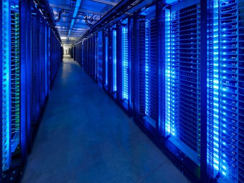 Server room aisle lit up with blue lighting.