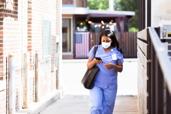 Nurse wearing a protective face mask walks to work. Used in post about Tebra, an operating system for independent healthcare providers