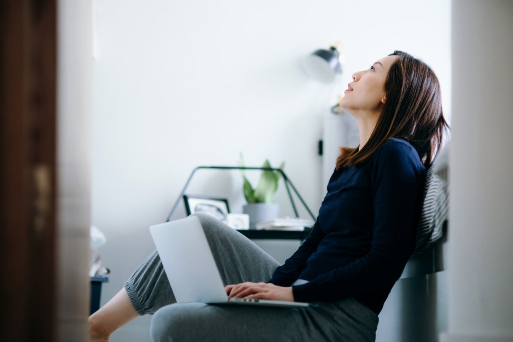Woman sitting on the floor of her bedroom with laptop, used in post about Asian mental health startup Intellect