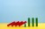 Falling red dominoes stopped by a small block to allow green dominoes to stay upright; mark to market startup valuations