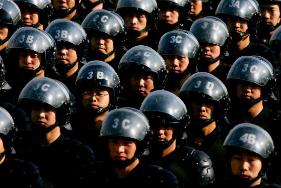 A group of Chinese police officers with helmets and riot gear.