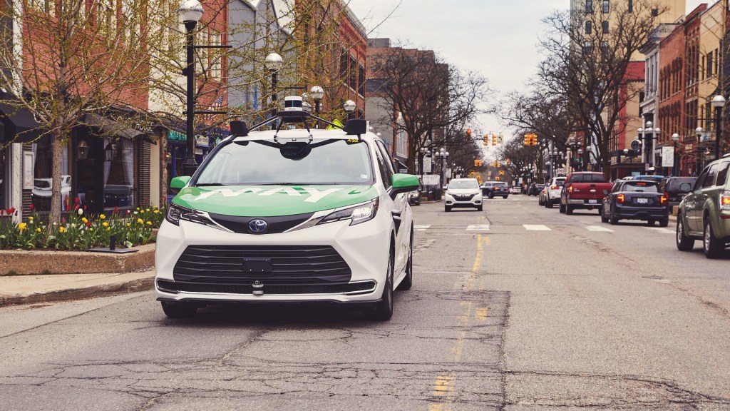Toyota Sienna Autono-MaaS with May Mobility green logo on hood driving down city street