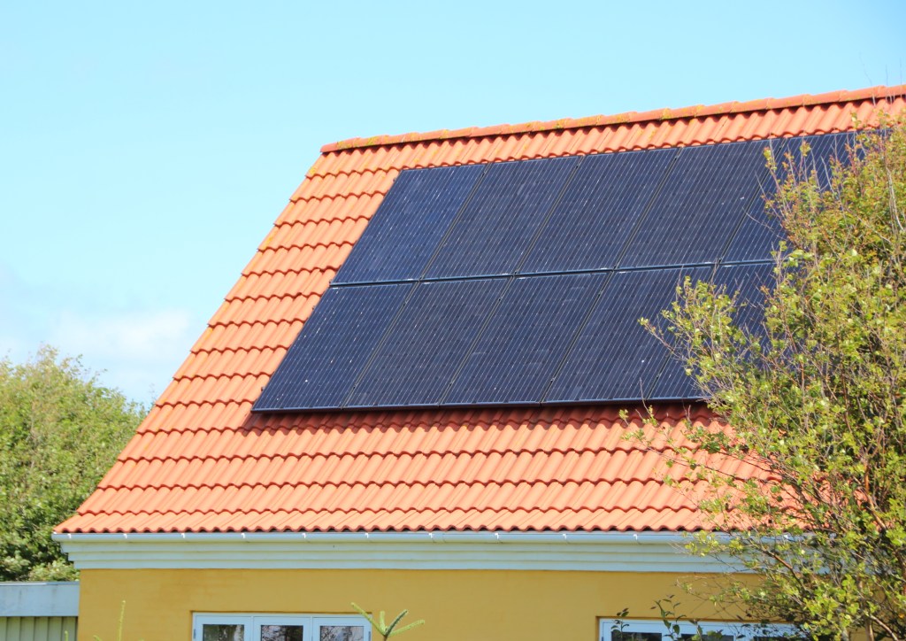 Solar panel on House Roof with Red Tiles and Blue sky