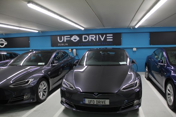 a row of black Teslas in front of UFODrive signage