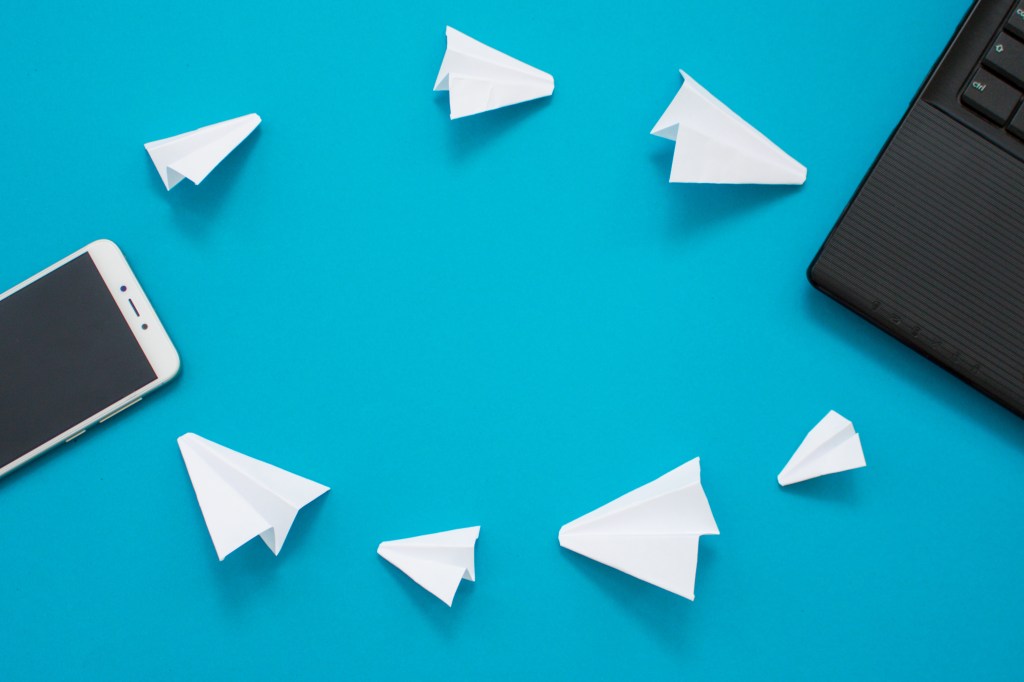 Image of white paper planes and gadgets on a blue background.