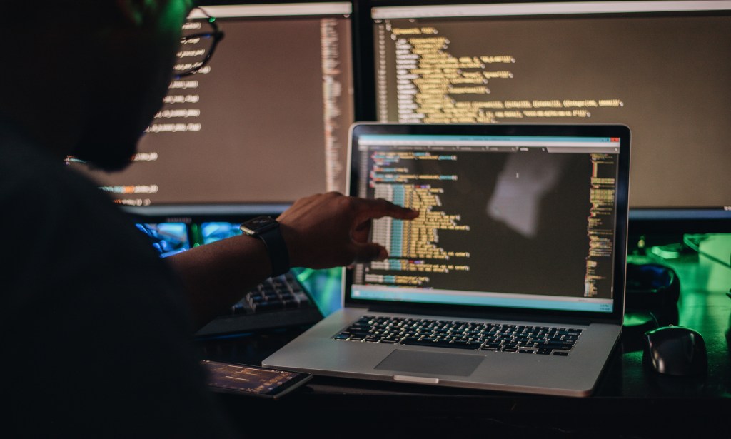 Man pointing at screen trying to see a part of his large code base.