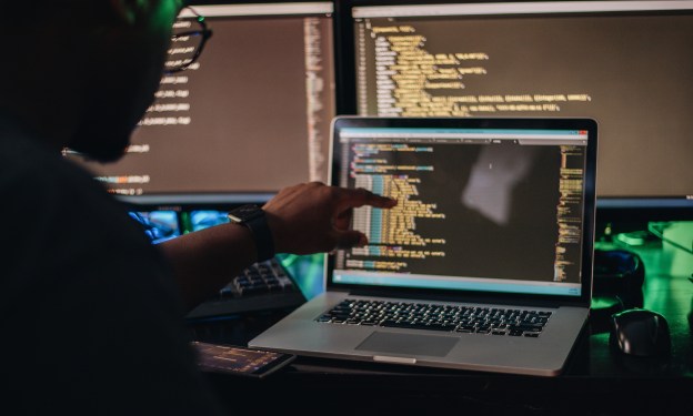 Man pointing at screen trying to see a part of his large code base.