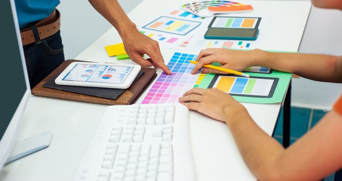 Two designers are designing colors of mobile app layouts.