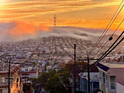 San Francisco brilliant sunset with fog rolling over Twin Peaks and Sutro Tower and clouds in sky.