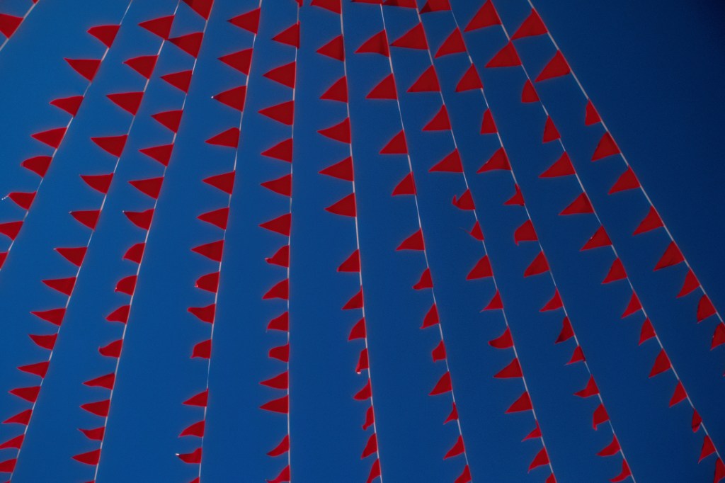 Image of red flags against a blue sky.