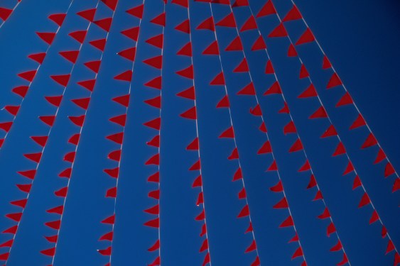 Image of red flags against a blue sky.