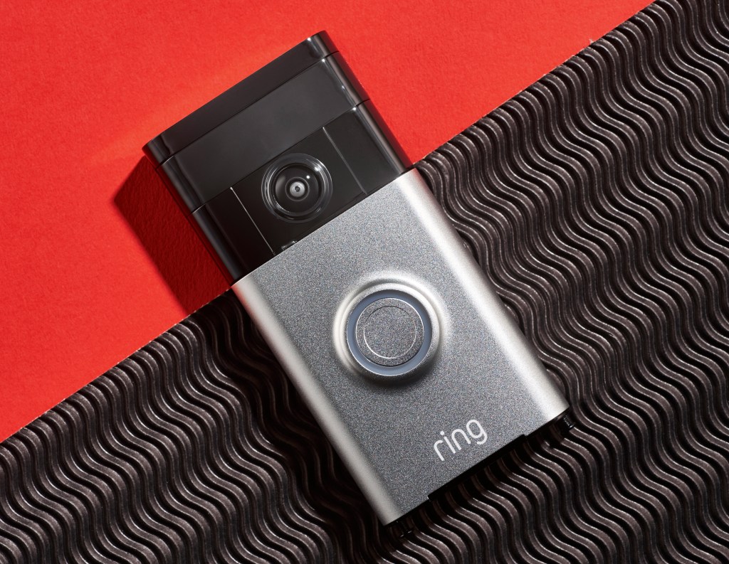 Ring video camera doorbell on a red plain and black textured background.