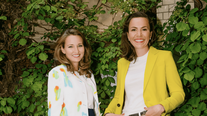 two women standing in front of ivy-covered brick wall