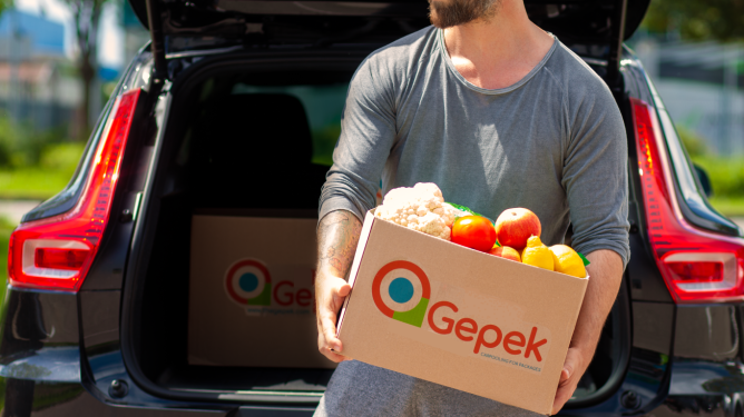 A man delivers a box with groceries out of the trunk of a car