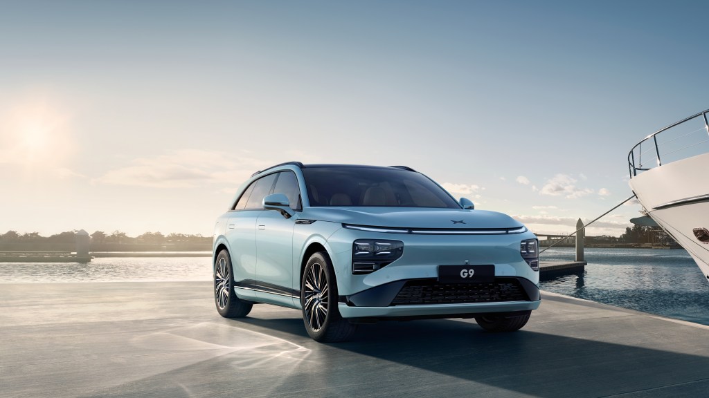 Xpeng flagship G9 SUV; silver luxury SUV with corner of a yacht to the right and marina in background