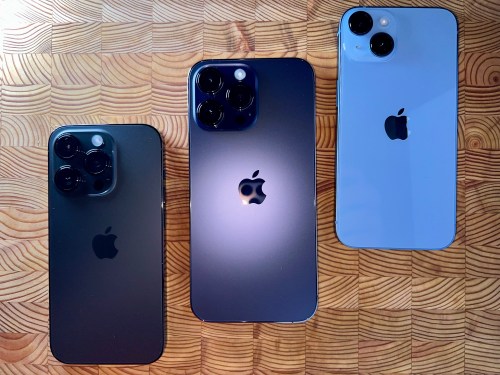 iPhone 14 pro space black, iPhone 14 pro deep purple and iPhone 14 blue colored iPhones on a wooden surface