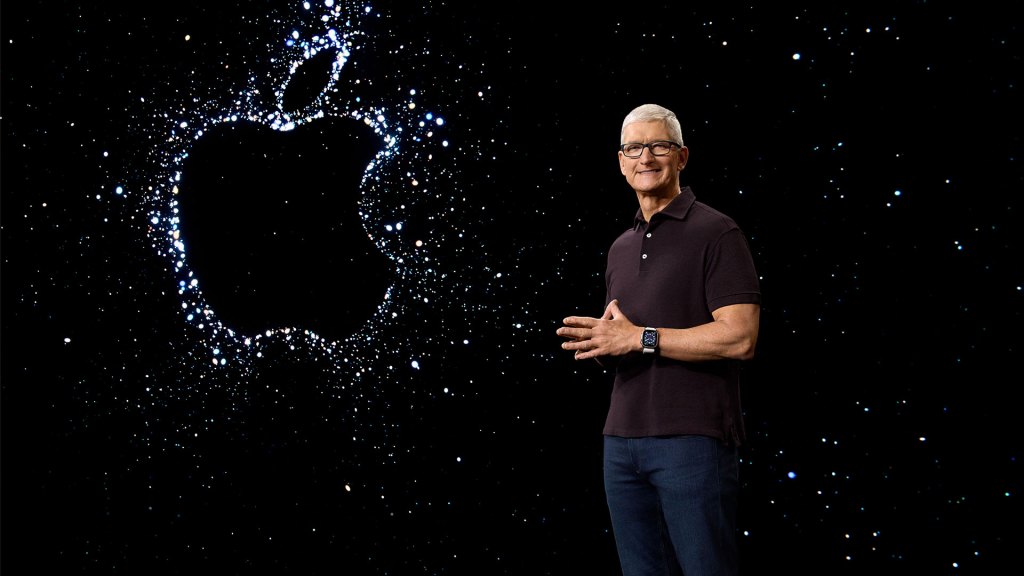 Tim Cook standing next to a sparkly Apple logo