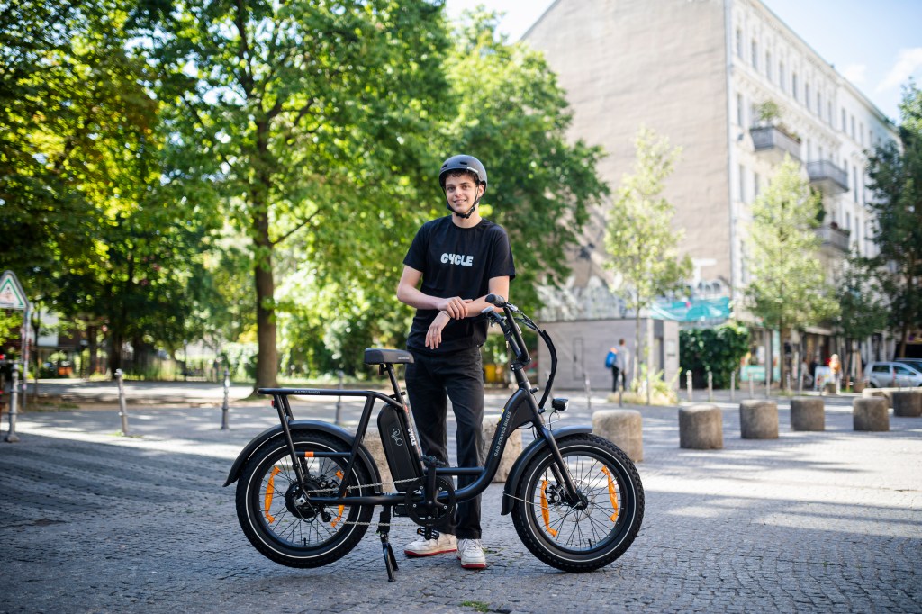 teenage boy wearing black tshirt that says 'cycle' standing behind rad power bikes e-bike