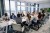 Diverse group of business executives seated at conference table and talking among themselves before start of meeting in board room.
