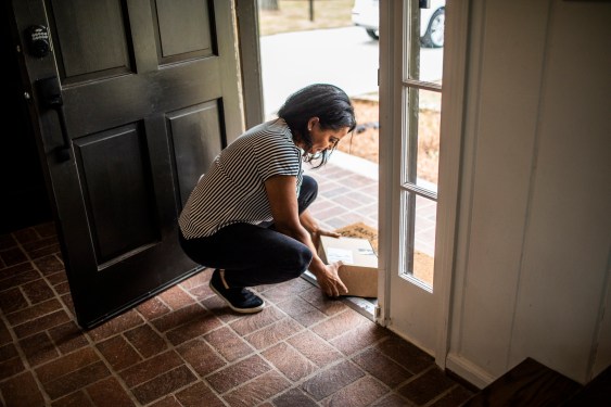 Woman picking up delivery package in residential doorway