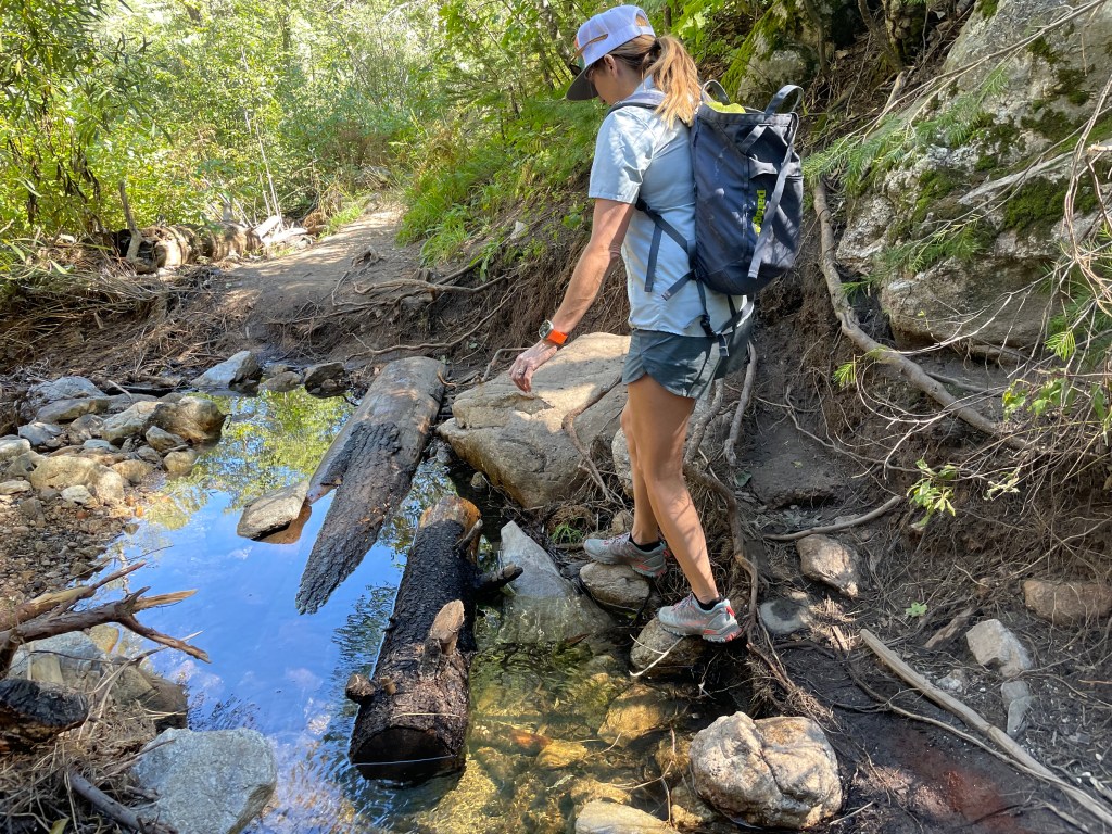 woman crossing stream on outdoor hike
