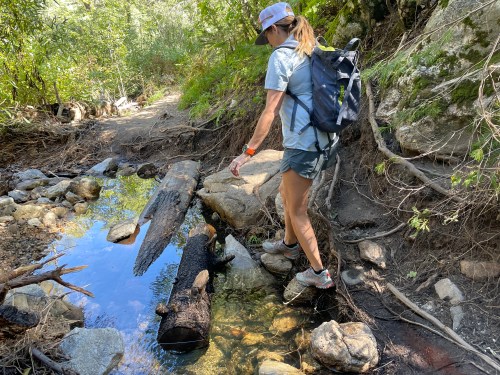 woman crossing stream on outdoor hike