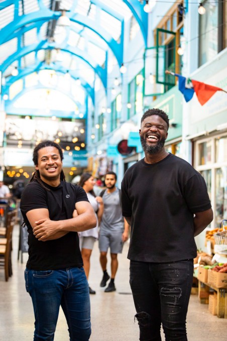 Two mean wearing Black shirts stand smiling at the camera