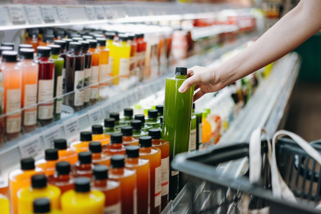 Image of a person reaching for a beverage in a supermarket.