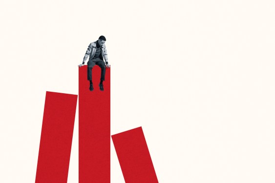 Successful young man sitting on top of red bar graph while looking down against white background