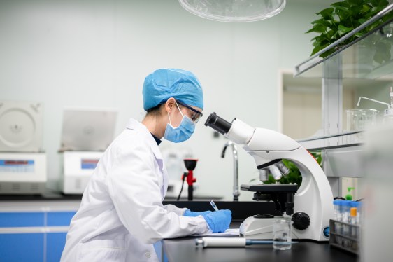 Woman in lab working at a microscope
