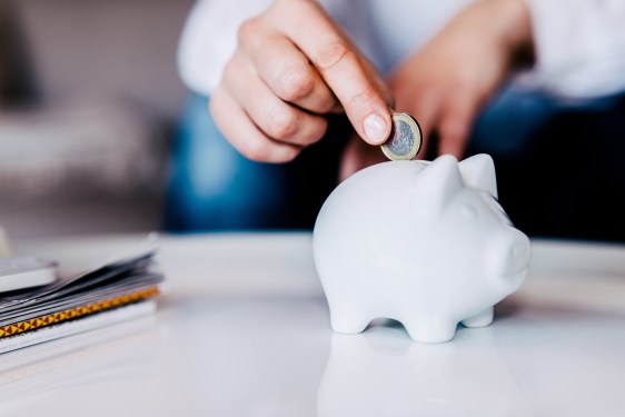 Putting a coin in a white piggy bank
