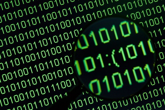 Magnifying glass showing word 'sad sign' in binary code on a computer display