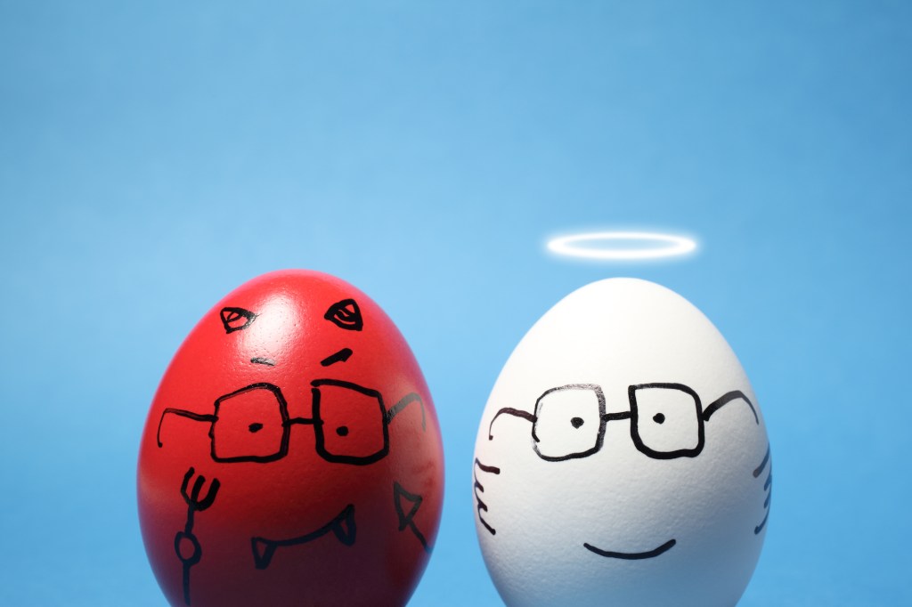 Close-up of devil and angel eggs, against blue background; investor ethics