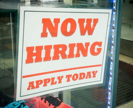 A Now Hiring sign in a shop window