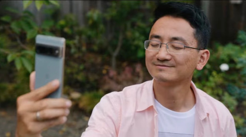 A man holds a Google Pixel 7 phone up to take a selfie. His eyes are closed.