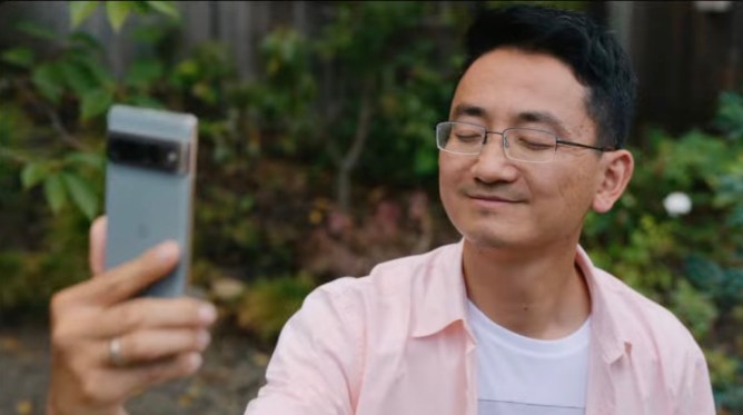 A man holds a Google Pixel 7 phone up to take a selfie. His eyes are closed.