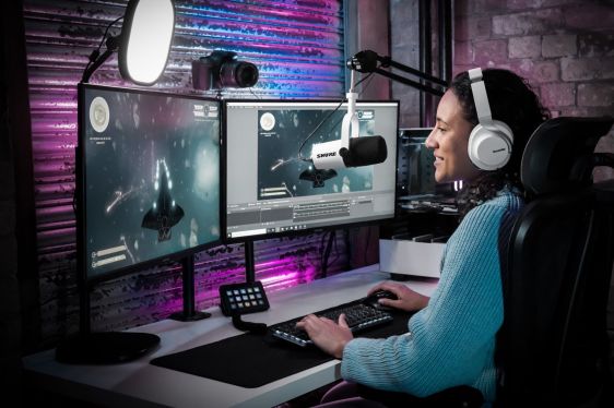 woman at workstation, wearing headphones and talking into mic
