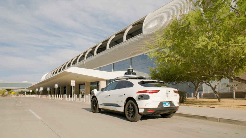 a waymo jaguar i-pace AV robotaxi approaching curb at phoenix 44th street sky train station
