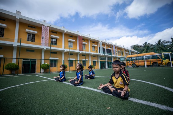 several children meditating on soccer pitch