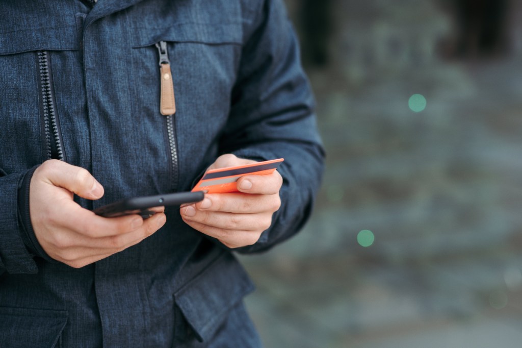person holding mobile phone and credit card; Phone payments