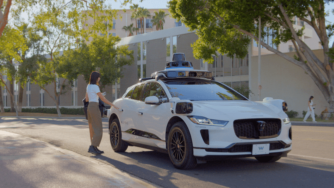 woman hails waymo robotaxi in downtown phoenix