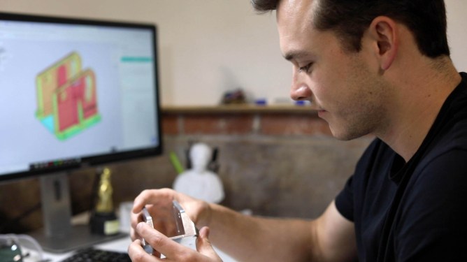 An engineer from Gecko Robotics, a Fictiv customer, holding a Fictiv part.