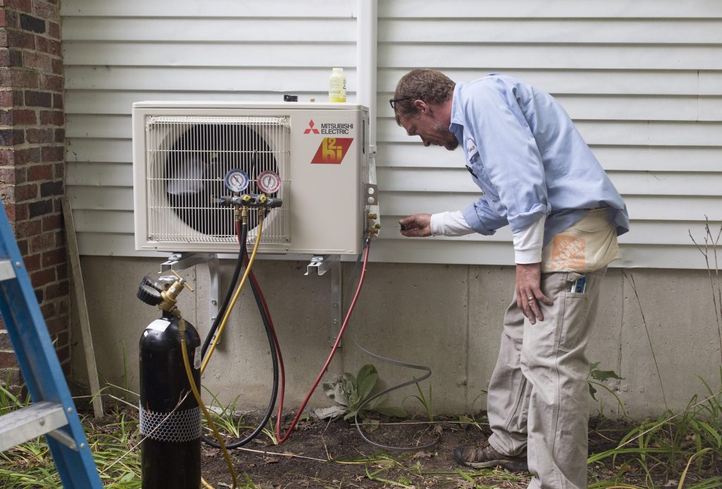 An HVAC technician installs a heat pump.