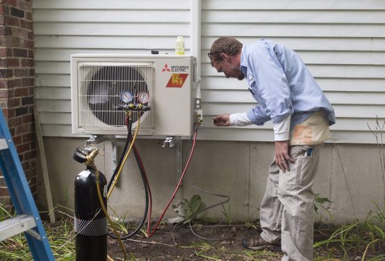 An HVAC technician installs a heat pump.