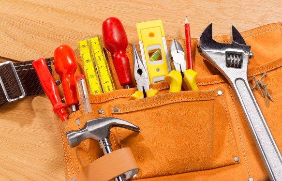 Tool belt full of tools laid out on wood floor