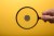 Human hand holding magnifying glass over american quarter on yellow background