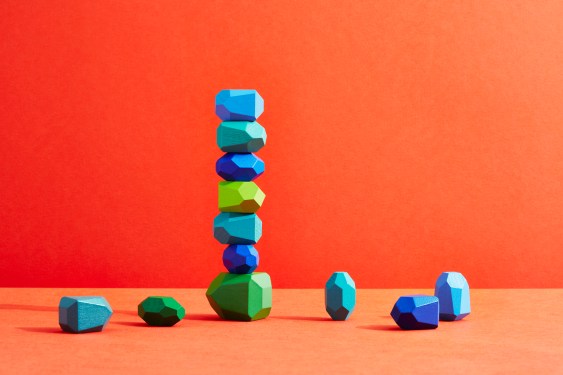 An incomplete stack of coloured pebbles on an orange background