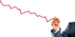 Closeup of businessman's hand drawing a graph with red line going down.